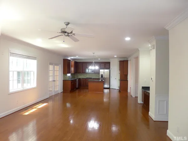 a view of an empty room with kitchen and window