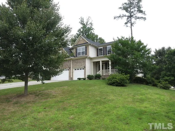 a view of a house with a big yard and large trees