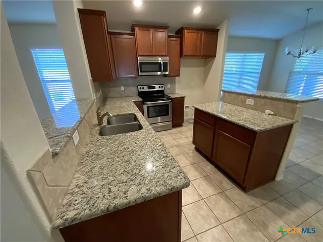 a kitchen with stainless steel appliances granite countertop a stove a sink and a microwave