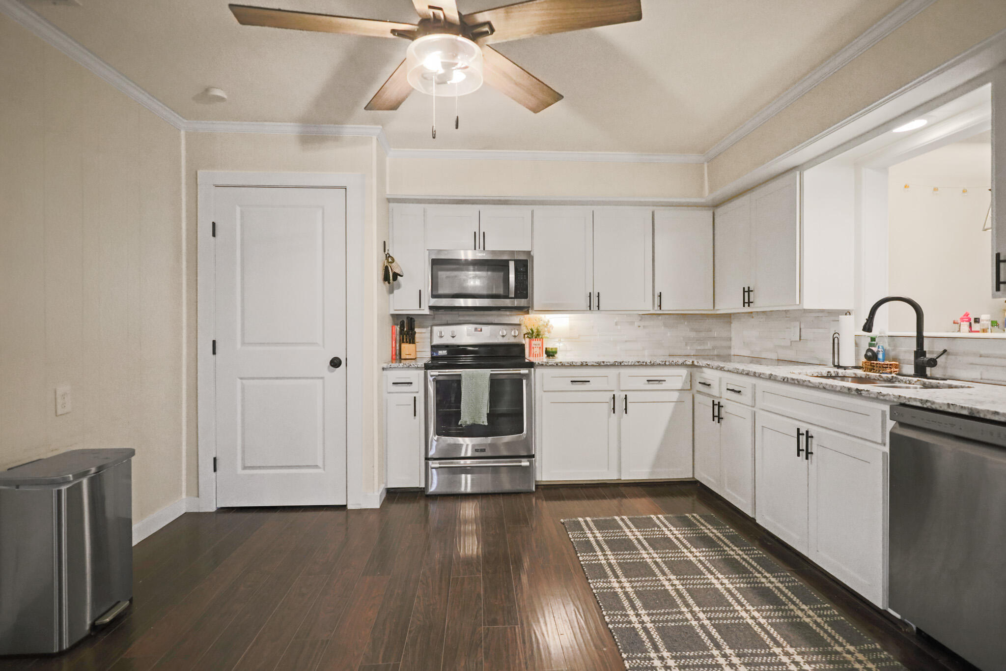 4302 42nd Street Lubbock, TX 79413 - Photo 18 of 67 a kitchen with granite countertop a stove top oven a sink and dishwasher with wooden floor