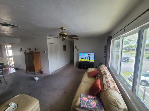 a living room with furniture a floor to ceiling window and a flat screen tv