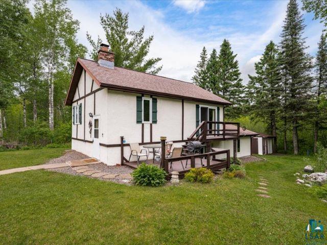 3616 Lavaque Road Hermantown, MN 55811 - Photo 22 of 43 Tudor-style exterior featuring a white facade with dark trim, a prominent brick chimney, and a multi-level deck