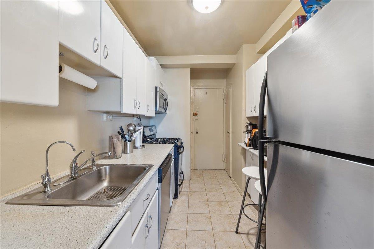 3 Fordham Hill Ovl, Unit 10B Bronx, NY 10468 - Photo 6 of 33 Kitchen with appliances with stainless steel finishes, a sink, white cabinets, and light countertops