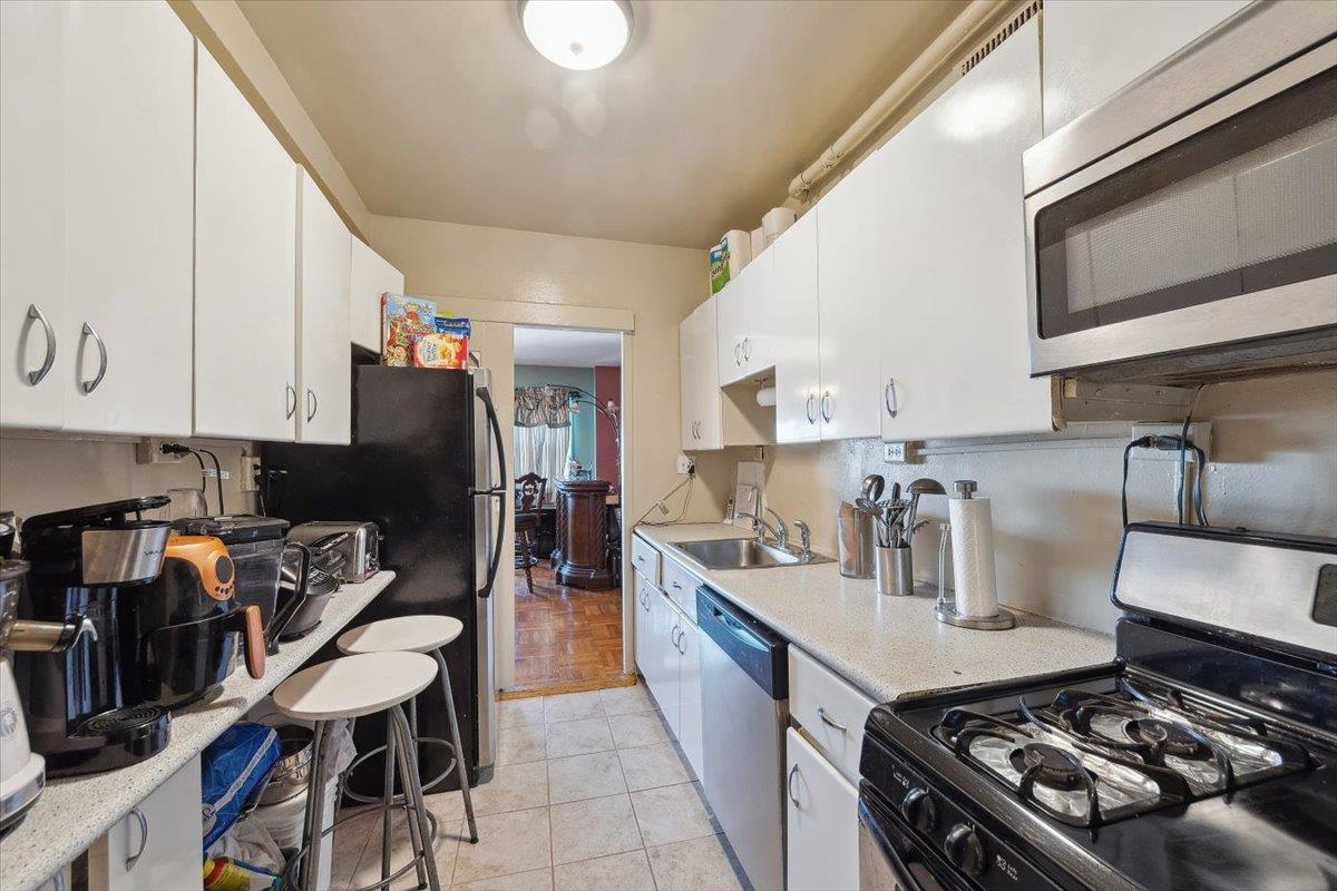 3 Fordham Hill Ovl, Unit 10B Bronx, NY 10468 - Photo 8 of 33 Kitchen featuring stainless steel appliances, a sink, white cabinetry, and light tile patterned flooring