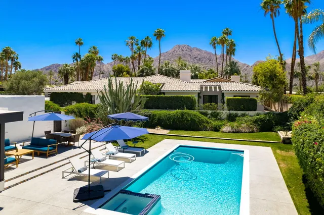 a view of swimming pool with a table and chairs under an umbrella