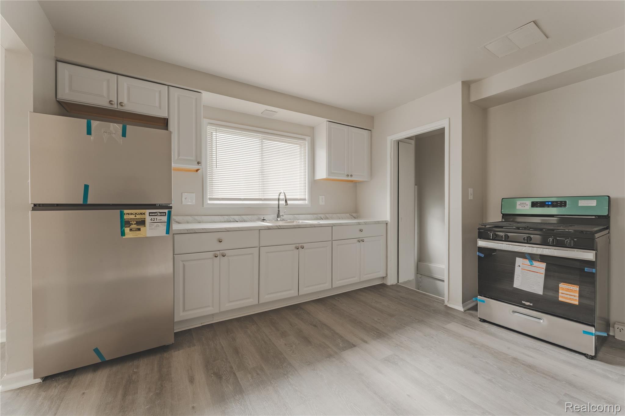 93 West Princeton Avenue Pontiac, MI 48340 - Photo 19 of 31 Kitchen featuring new stainless steel appliances, white cabinetry, a single basin sink with a chrome faucet, light-toned countertops, and wood-finish flooring