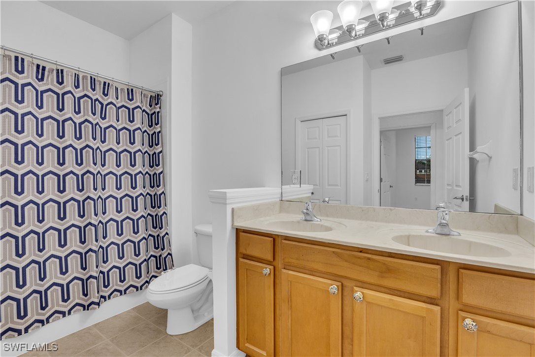 3799 Costa Maya Way, Unit 202 Estero, FL 33928 - Photo 24 of 42 a bathroom with a granite countertop sink a toilet and a mirror