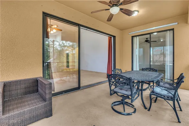 an empty room with a ceiling fan and kitchen view