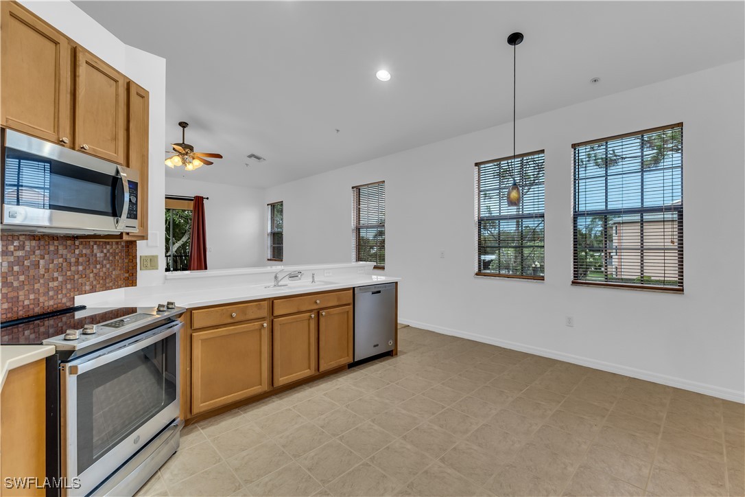 3799 Costa Maya Way, Unit 202 Estero, FL 33928 - Photo 4 of 42 a kitchen with stainless steel appliances granite countertop a stove a sink and a refrigerator with wooden floor