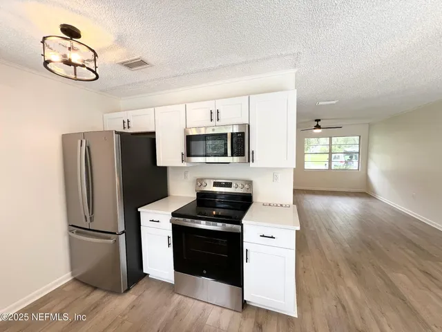 a kitchen with a refrigerator and white cabinets