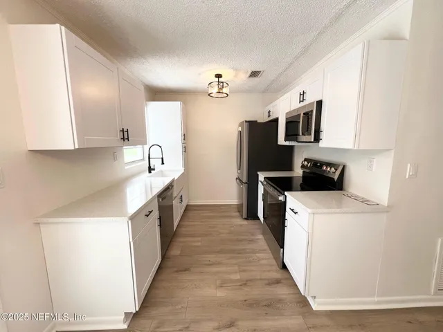 a kitchen with stainless steel appliances a refrigerator a stove top oven a sink and dishwasher