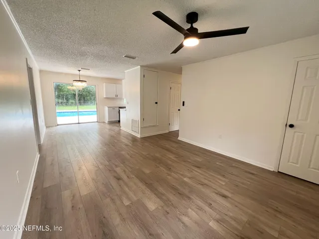 a view of empty room with wooden floor and fan