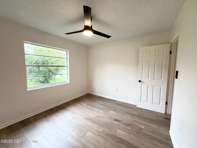 an empty room with wooden floor chandelier and windows