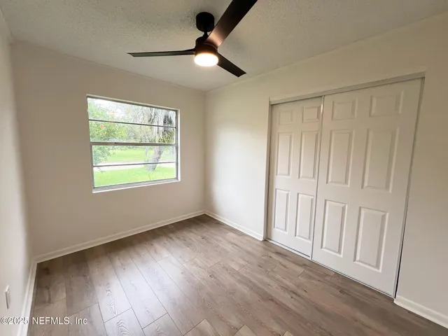 an empty room with wooden floor fan and windows