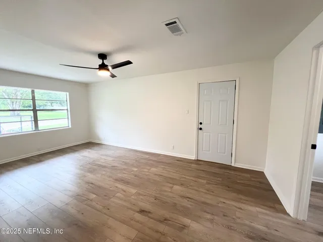 a view of empty room with wooden floor and fan
