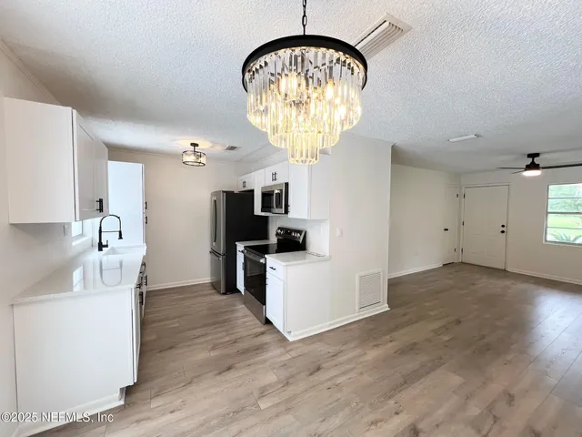 a view of a kitchen with electric equipment and wooden floor