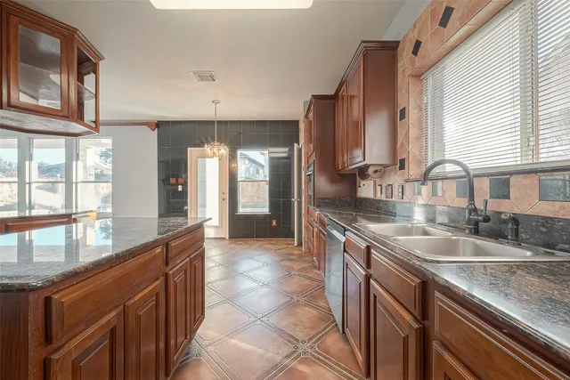a kitchen with granite countertop a sink and a refrigerator