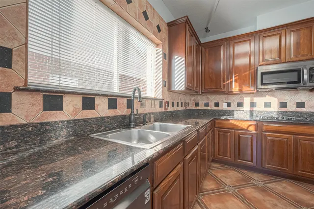 a kitchen with granite countertop stainless steel appliances a sink a stove a refrigerator a sink and cabinets