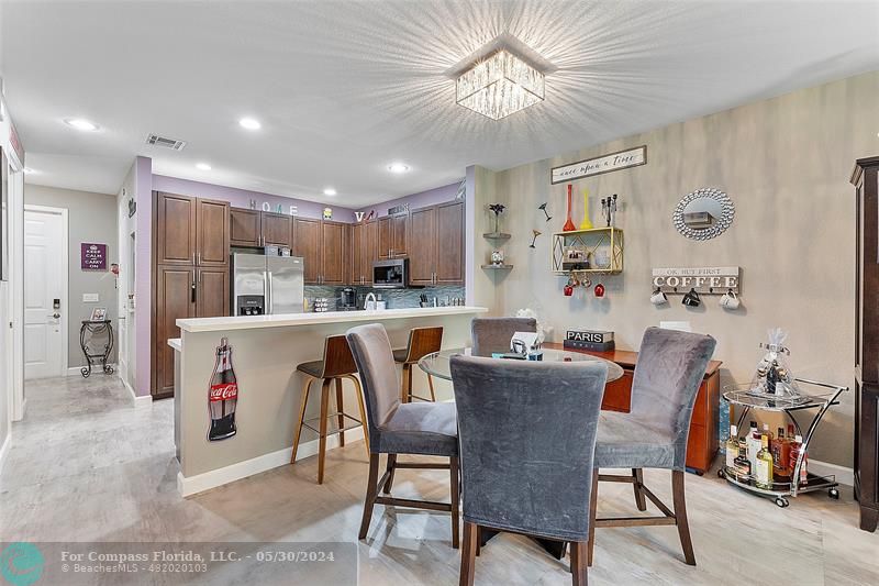 7774 Paddock Place, Unit 7774 Davie, FL 33328 - Photo 10 of 28 a dining room with stainless steel appliances kitchen island granite countertop a dining table chairs and a refrigerator