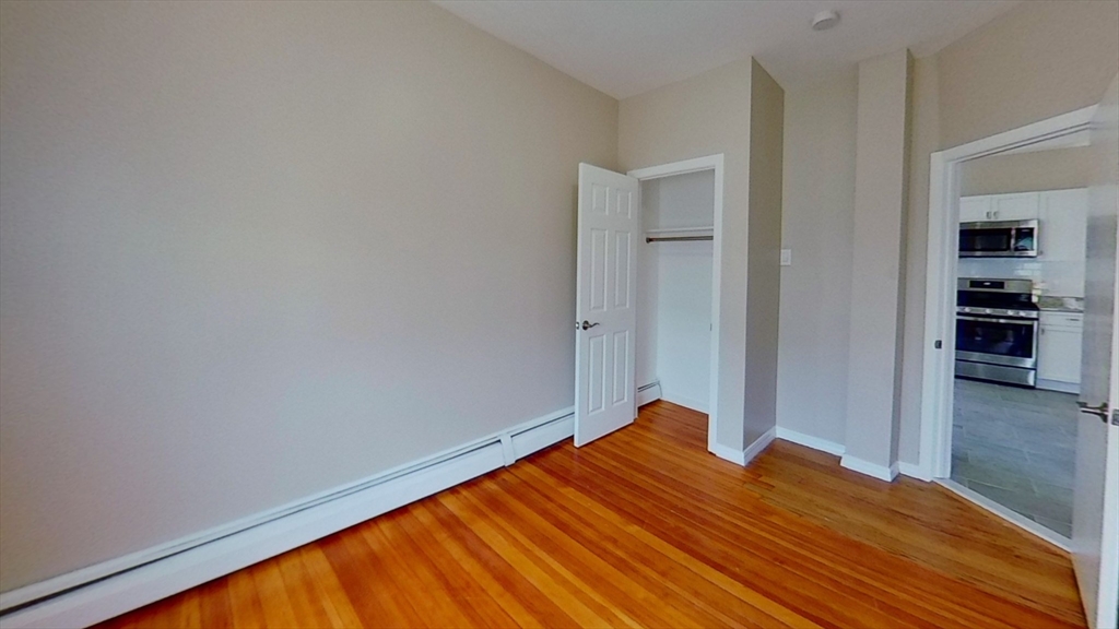 119 George Street, Unit 3 Boston, MA 02119 - Photo 3 of 8 a bedroom with a bed and wooden floor
