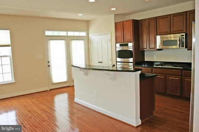 a kitchen with kitchen island granite countertop wooden floors and wide window