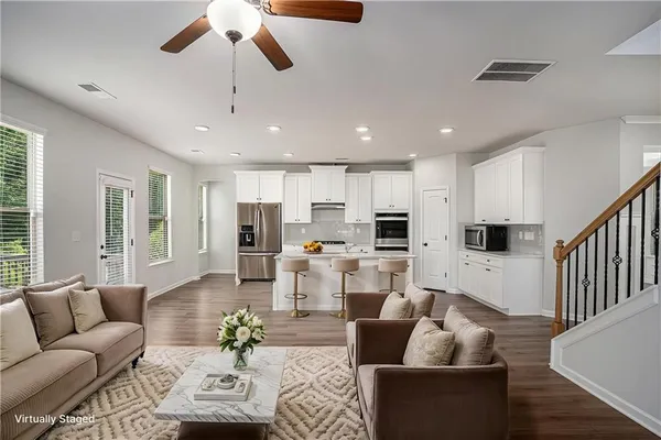 a living room with furniture kitchen view and a large window