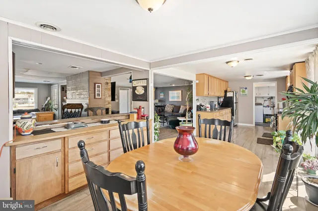 a view of a dining room and livingroom with furniture wooden floor a rug a painting and a chandelier