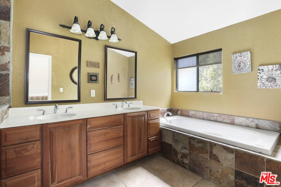 1926 Corral Canyon Road Malibu, CA 90265 - Photo 21 of 29 a spacious bathroom with a granite countertop sink and a mirror