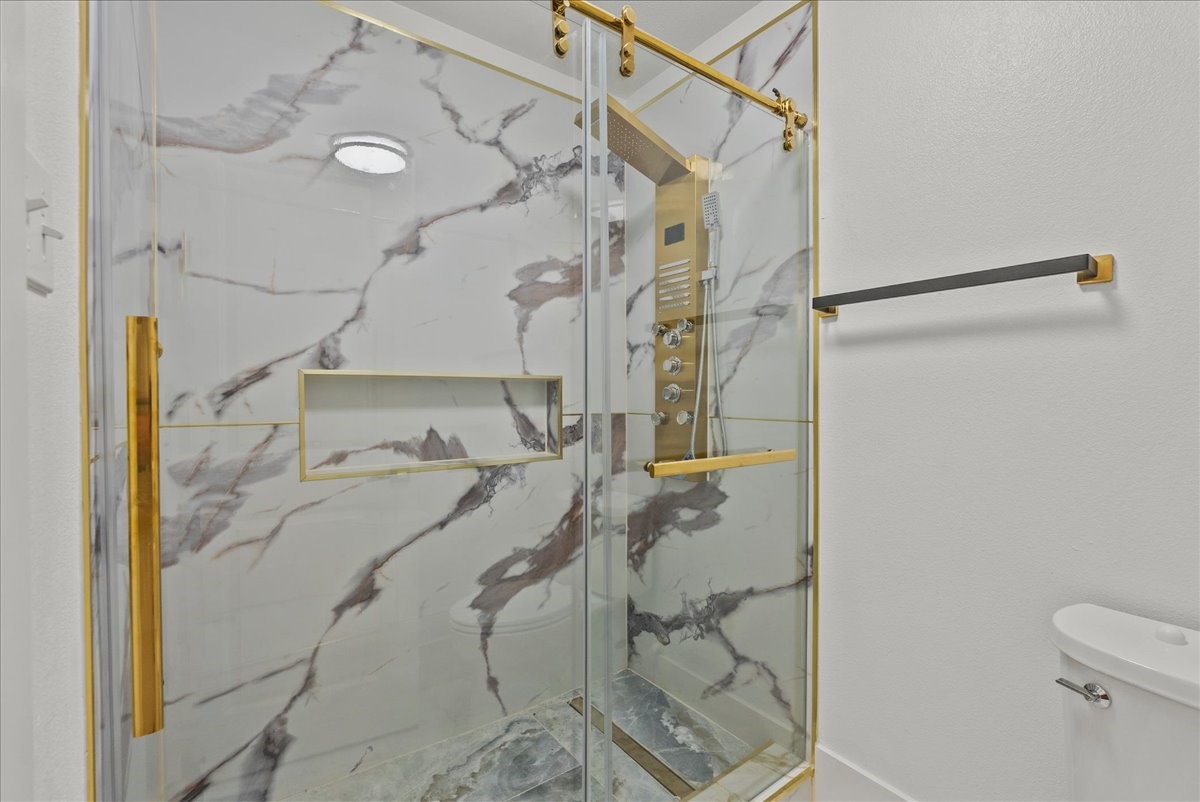 3237 Harkey Road Pearland, TX 77584 - Photo 28 of 46 Spa-inspired walk-in shower with dramatic marble-look tile and gold accents.