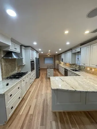 a large kitchen with stainless steel appliances kitchen island granite countertop a large counter top and a sink