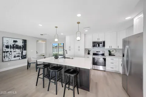 a kitchen with stainless steel appliances a dining table chairs stove refrigerator and cabinets