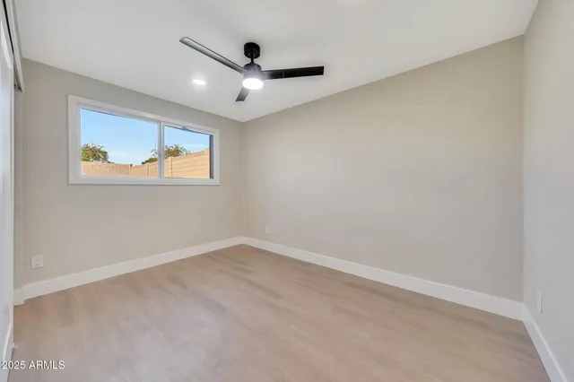 an empty room with windows and ceiling fan