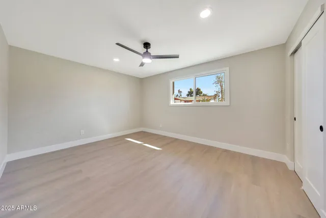 an empty room with a ceiling fan and window