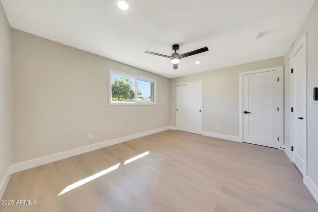 an empty room with wooden floor ceiling fan and windows