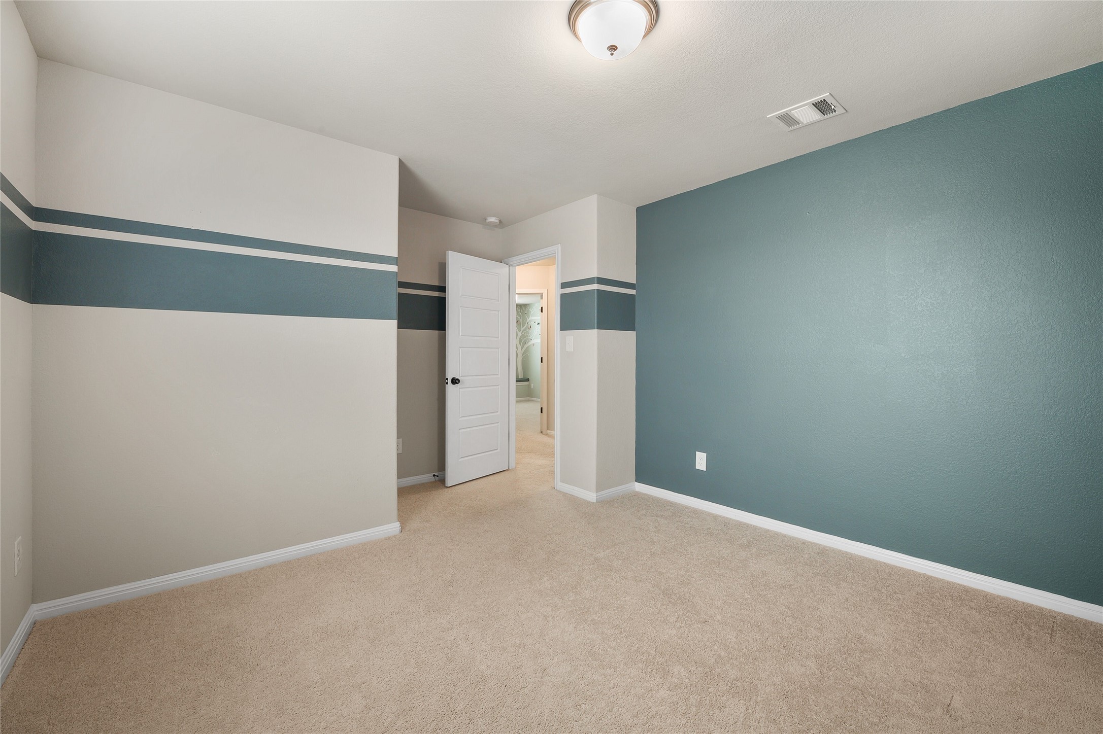 101 Lambert Street Leander, TX 78641 - Photo 21 of 33 A well-lit bedroom with fresh carpet and a stylish accent wall, ready for personalization.