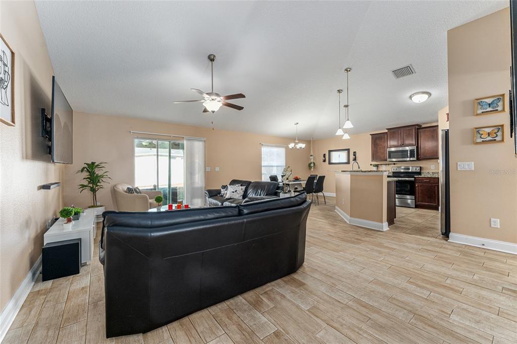 9961 Southwest 55th Ave Road Ocala, FL 34476 - Photo 13 of 89 a living room with stainless steel appliances kitchen island granite countertop furniture a flat screen tv and a refrigerator