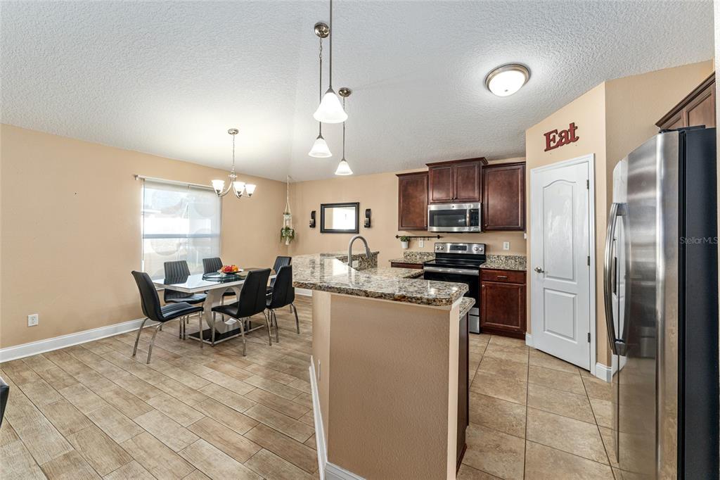 9961 Southwest 55th Ave Road Ocala, FL 34476 - Photo 28 of 89 a kitchen with stainless steel appliances granite countertop a refrigerator oven a sink dishwasher a dining table and chairs with wooden floor