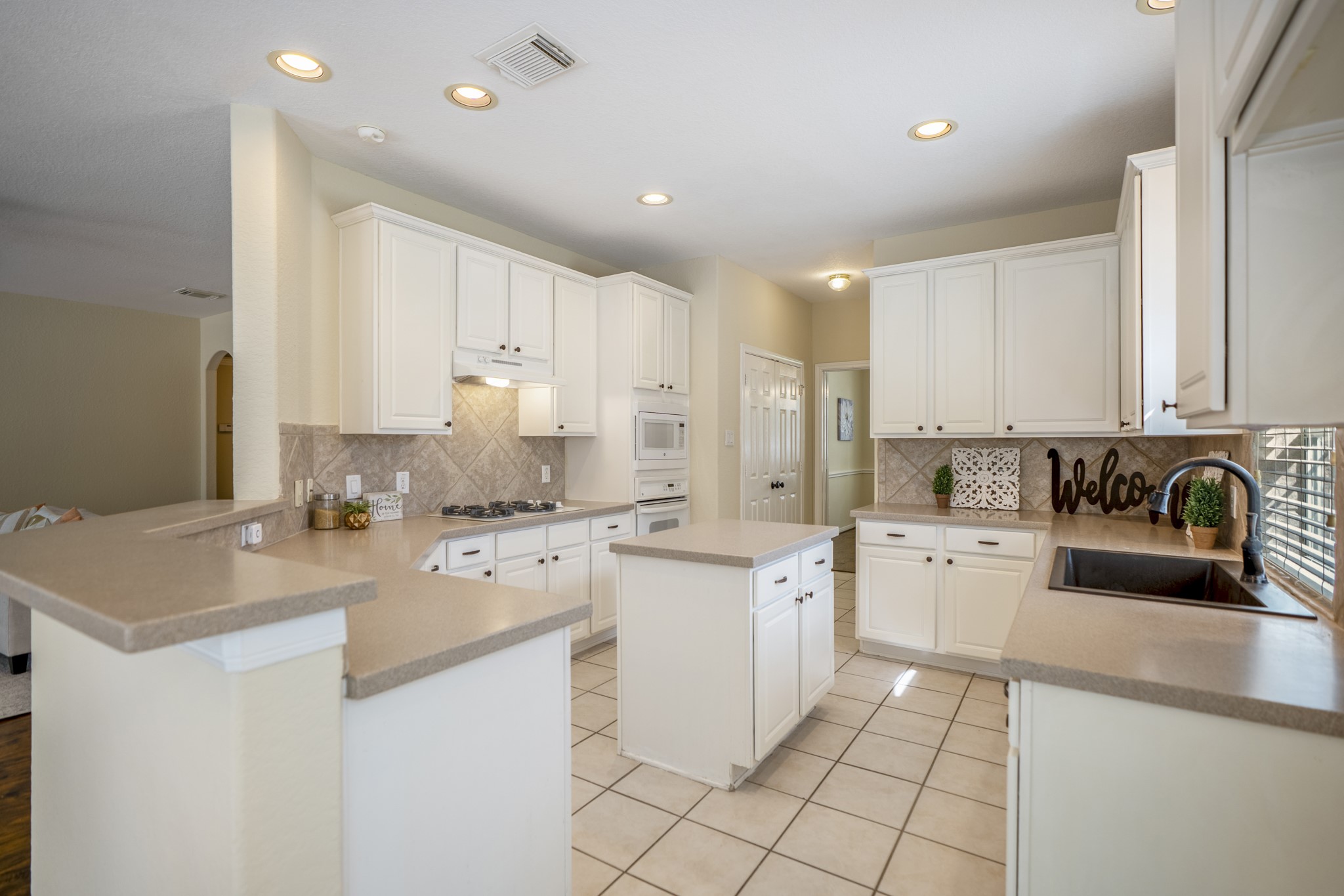 5807 Sequoia Trace Court Spring, TX 77379 - Photo 11 of 50 Hosting is a breeze in this beautiful kitchen with corian counters, island with storage, gas cooktop, built-in appliances, and long stretches of cabinetry, with the breakfast bar keeping the space connected to the family room.