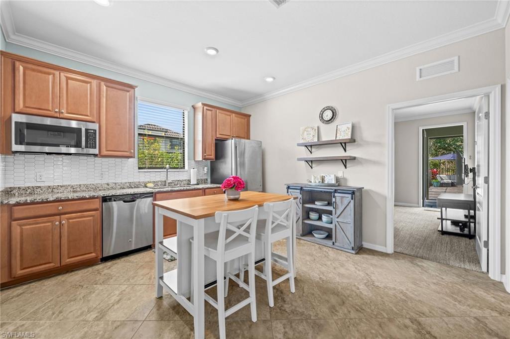 4754 Abaca Circle Naples, FL 34119 - Photo 30 of 46 a kitchen with stainless steel appliances granite countertop a stove top oven a sink a dining table and chairs