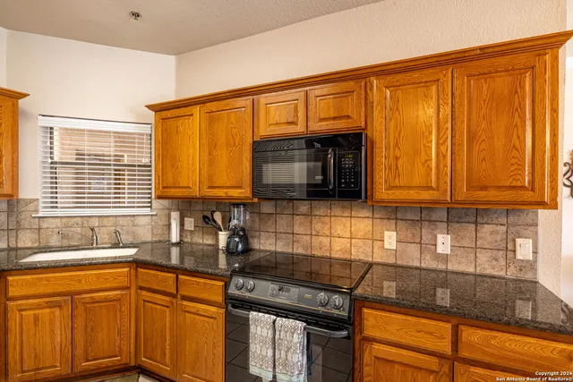 a kitchen with granite countertop cabinets stainless steel appliances a sink and a window