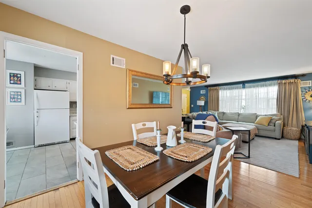 a view of a dining room and livingroom with furniture wooden floor a chandelier