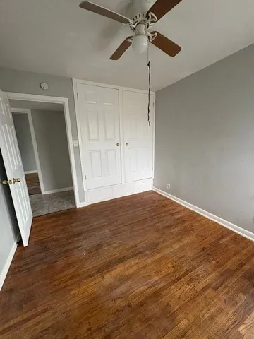 an empty room with wooden floor fan and windows