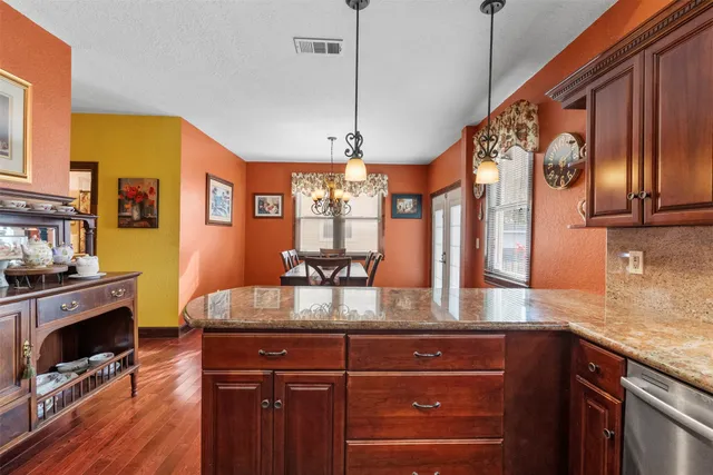 a kitchen with stainless steel appliances granite countertop a sink a stove and wooden floors