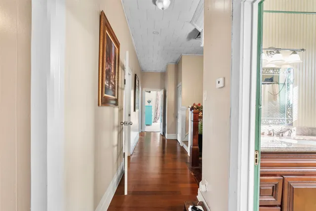a view of a hallway with wooden floor windows and a bathroom