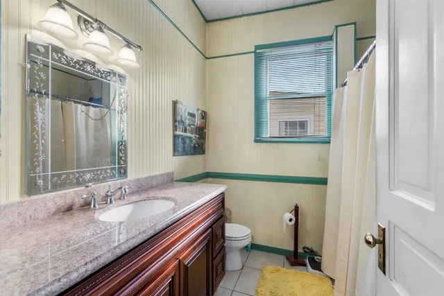 a bathroom with a granite countertop sink a mirror a toilet and a shower