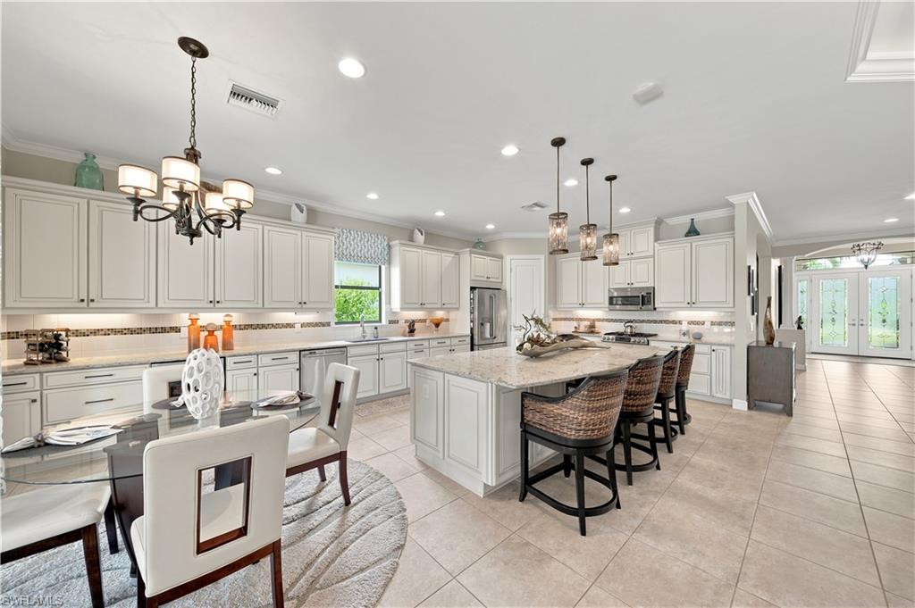 9256 Rialto Lane Naples, FL 34119 - Photo 10 of 43 Spacious open-concept living area featuring a gourmet kitchen with white shaker cabinetry, granite countertops, and stainless steel appliances