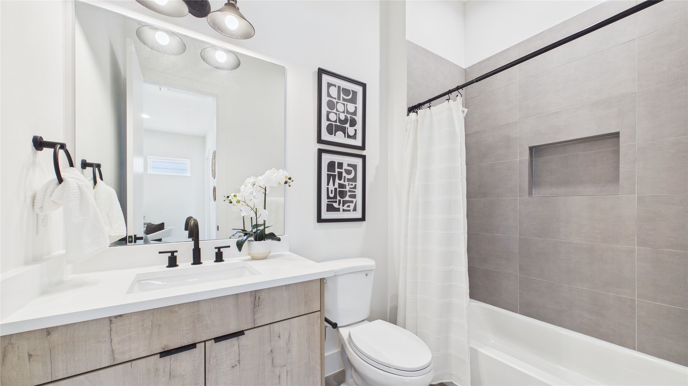6058 Cebra Street Houston, TX 77091 - Photo 34 of 38 The secondary bathroom upstairs is adorned with tiling and a soap nook in the bath/shower combination. The quartz vanity and large mirror provide the area needed to get ready for the day!
