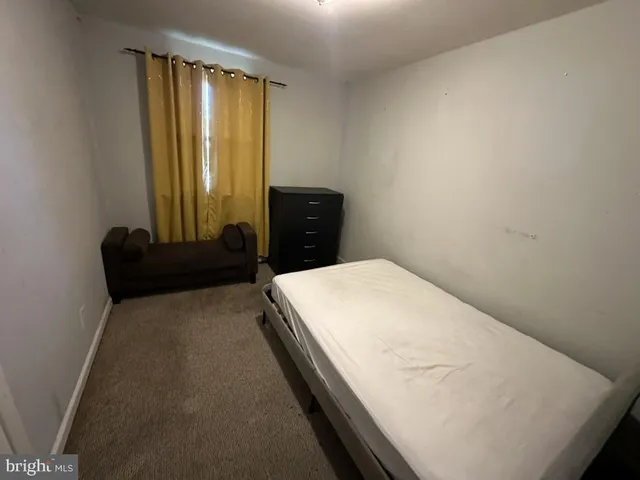 a bed sitting in a spacious bedroom next to a window