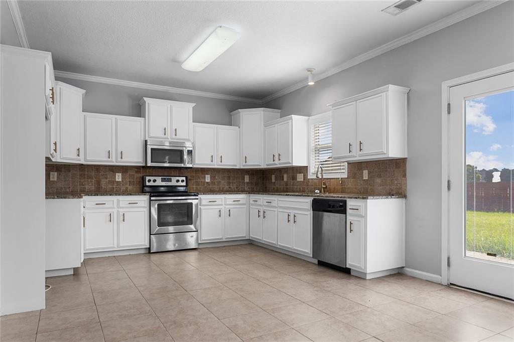 6 Pebblebrook Lane Fort Mitchell, AL 36856 - Photo 8 of 48 Kitchen featuring backsplash, stainless steel appliances, ornamental molding, white cabinets, and dark stone countertops
