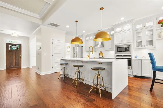 a kitchen with stainless steel appliances kitchen island granite countertop a table chairs and a wooden floor